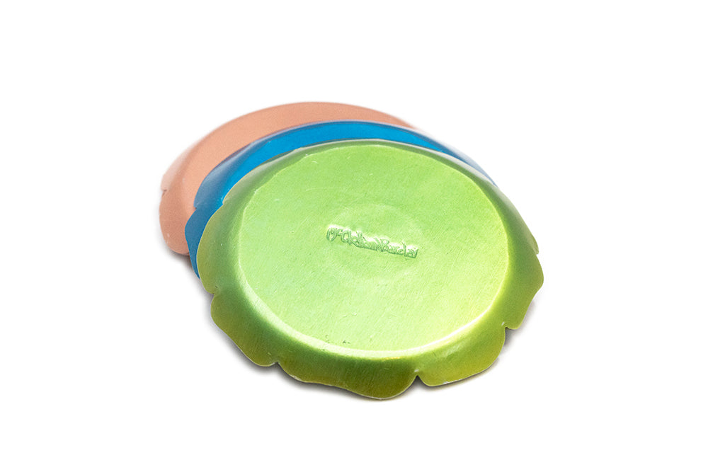 View of a stack of vintage 1930s  McClelland Barclay colourful aluminum coasters showing the makers stamp on the green coaster 