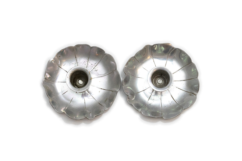 A pair of vintage McClelland Barclay silver color aluminum flower-shaped taper candle holders with scalloped petals, shown from above on a plain white background.