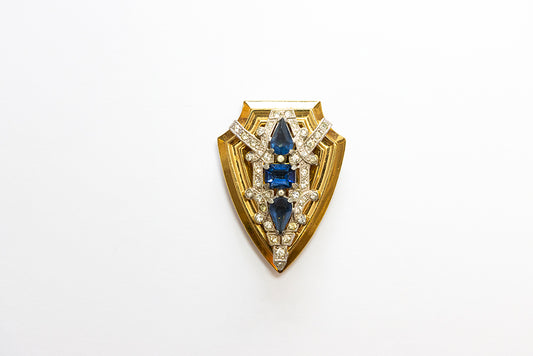 Vintage shield shaped MCCLELLAND BARCLAY Art Deco dress clip is gold plated with blue and clear rhinestones 