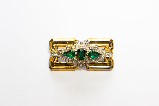 A gold-plated rectangular Art Deco style brooch featuring a central green square-cut rhinestone flanked by two pear-shaped green stones, accented with clear pavé rhinestones on a white background.