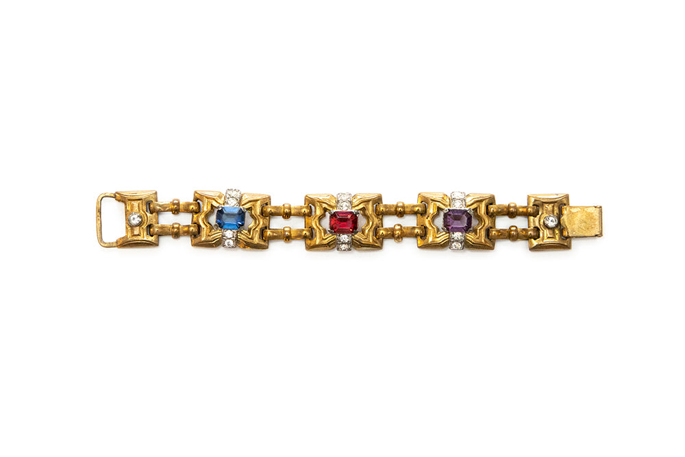 Vintage McClelland Barclay Art Deco gold plated bracelet featuring alternating square links with blue, red, and purple rhinestones, accented by small clear rhinestones, shown on a white background