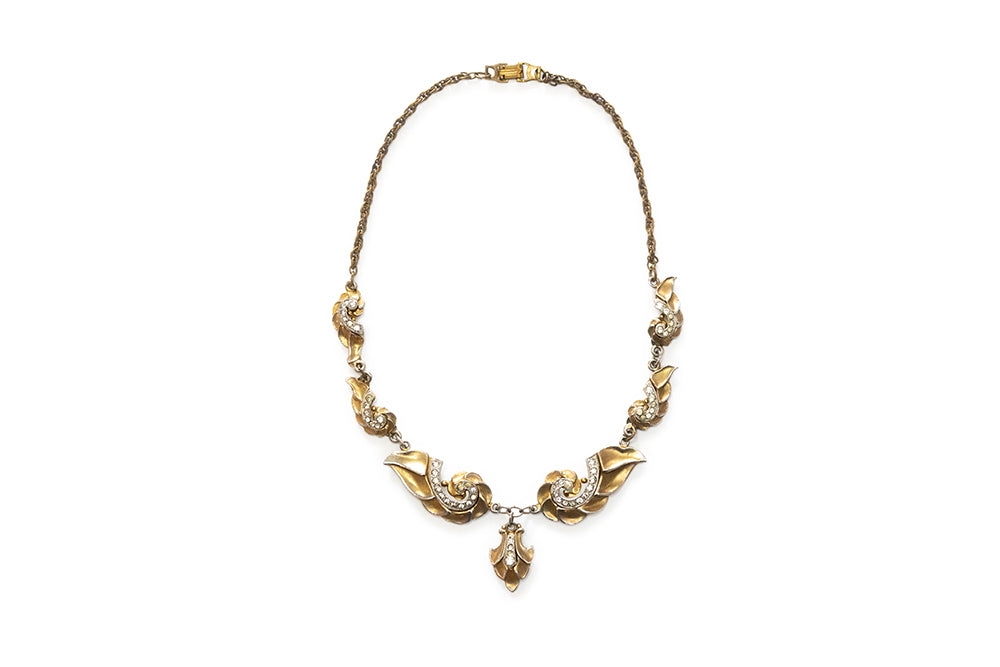 Vintage McClelland Barclay gold plated necklace with swirl designs embellished with clear rhinestones on a white background