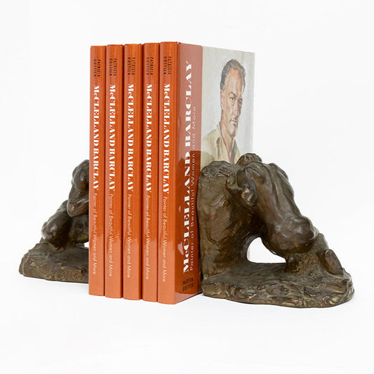 angled view of bronze plated Sisyphus bookends by McClelland Barclay Art Products from the 1930s shown with illustrated biography book of the artist