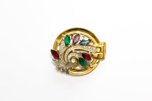 A large McClelland Barclay Art Moderne gold tone brooch features a swirl of multi-colored navette shaped rhinestones and clear pave stones