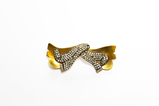 A curled pavé rhinestone gold tone bow brooch is an Art Moderne 1940s vintage jewelry design by McClelland Barclay